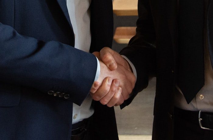 Dos personas cerrando un acuerdo con un apretón de manos